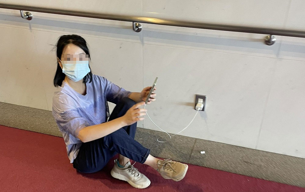 一名中国女子在日本公共场所使用多功能厕所的插座为手机充电
